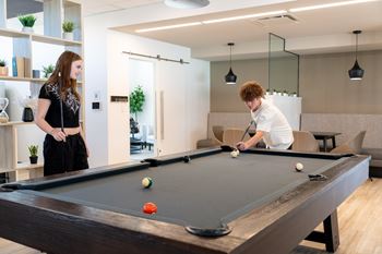 A man and a woman are playing pool in a room with a pool table.